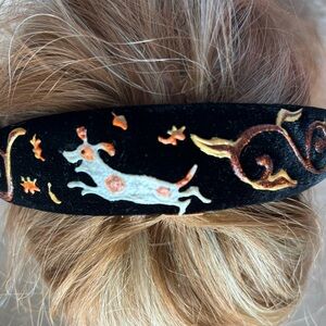 Black velvet hair band with dog playing in autumn leaves.